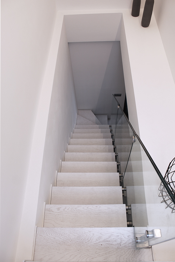 escalera_interior_de_diseno_con_zancas_laterales_y_barandilla_de_vidrio.jpg